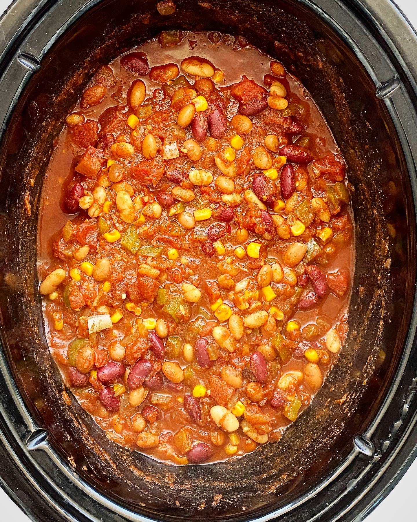 overhead shot of cooked ingredients for the best crockpot vegan chili in a black slow cooker