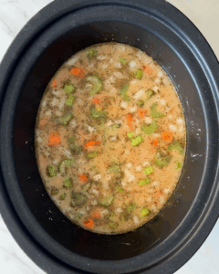 overhead shot of uncooked Corn And Crab Chowder in a black slow cooker
