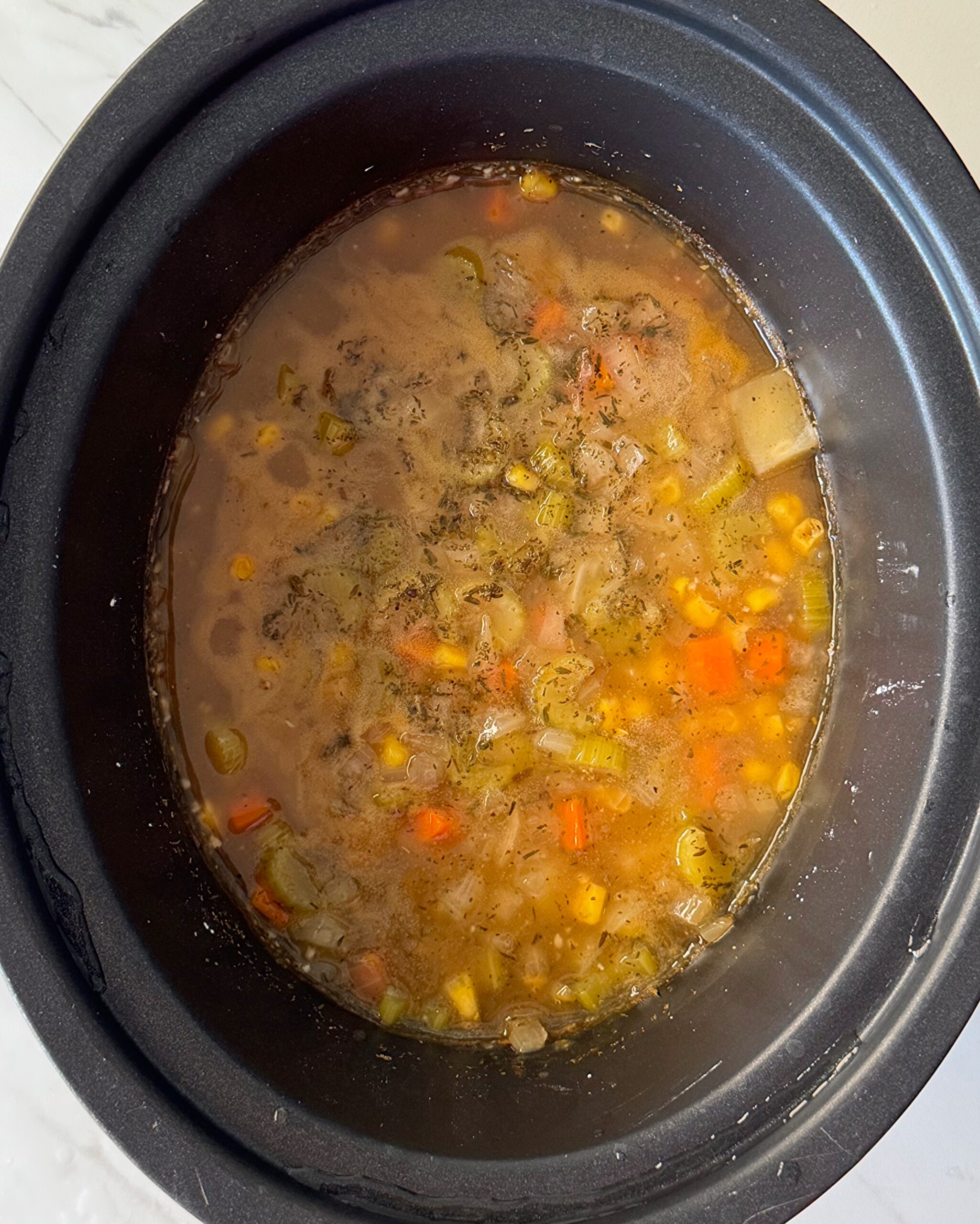 overhead shot of cooked Corn And Crab Chowder in a black slow cooker