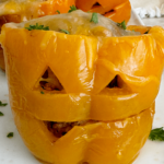 close up shot of cooked Crockpot Jack-O-Lantern Stuffed Peppers on a white plate