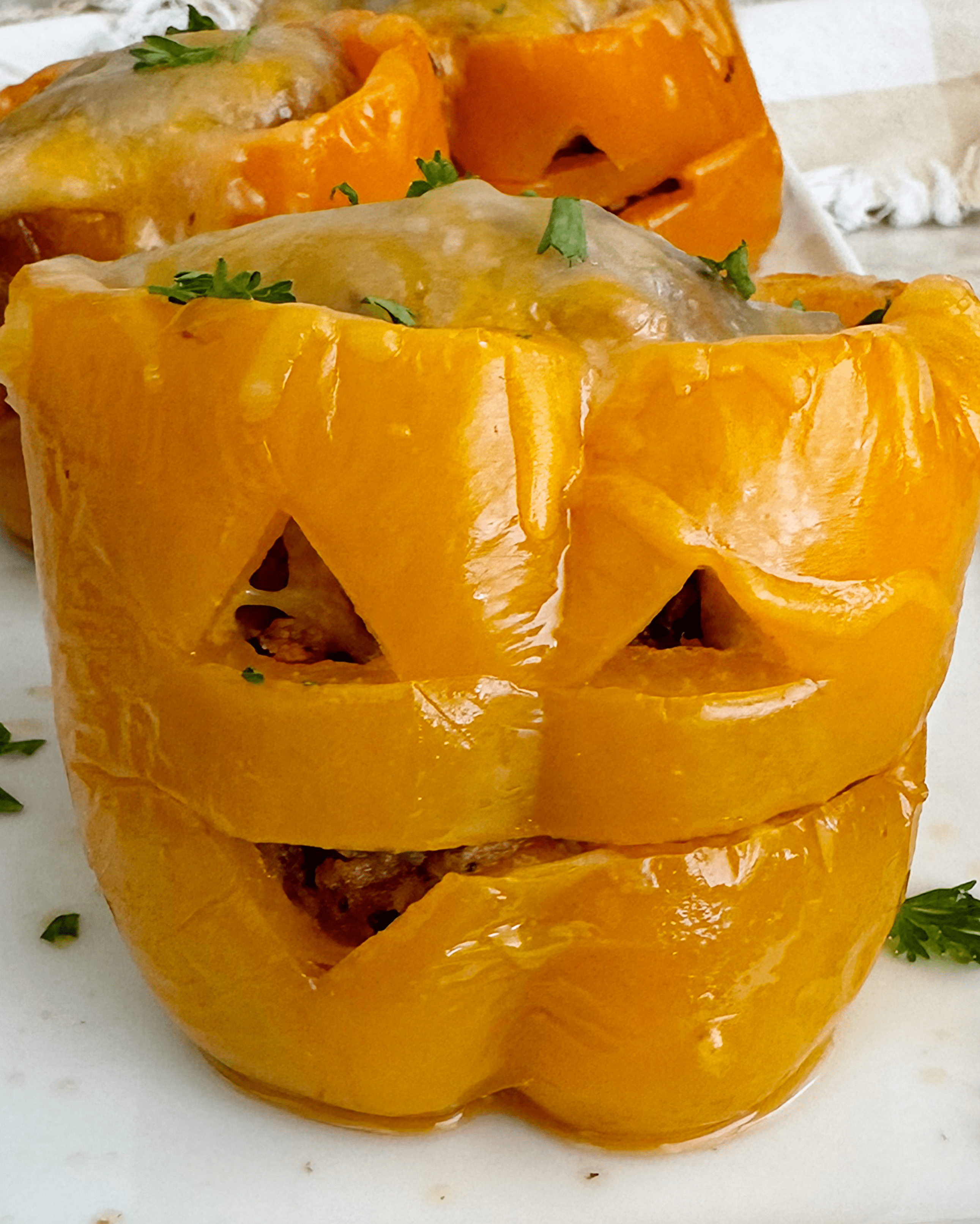 close up shot of cooked Crockpot Jack-O-Lantern Stuffed Peppers on a white plate