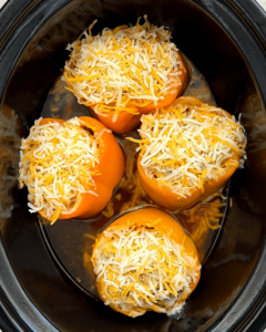 overhead shot of cooked Jack-O-Lantern Stuffed Peppers in a black slow cooker