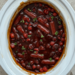 overhead shot of Cranberry BBQ Cocktail Sausages in a white slow cooker