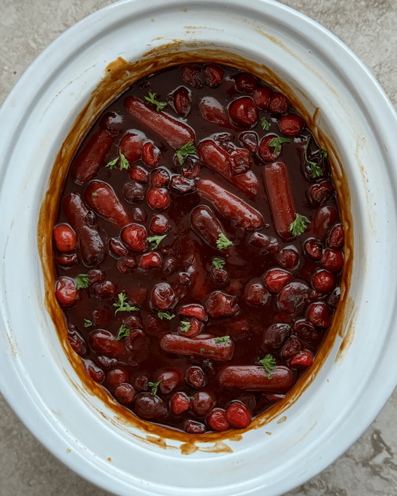 overhead shot of Cranberry BBQ Cocktail Sausages in a white slow cooker
