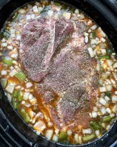 overhead shot of uncooked slow cooker pork and beans in a black slow cooker