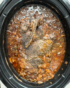 overhead shot of cooked slow cooker pork and beans in a black slow cooker