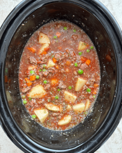 overhead shot of uncooked poor man's stew in a black slow cooker