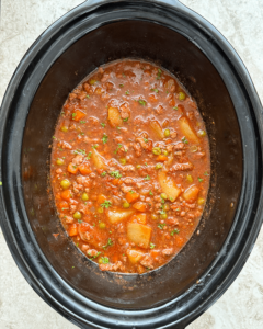 overhead shot of uncooked poor man's stew in a black slow cooker