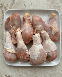 overhead shot of raw chicken legs on a white plate