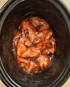 overhead shot of cooked BBQ chicken tenders in a black slow cooker