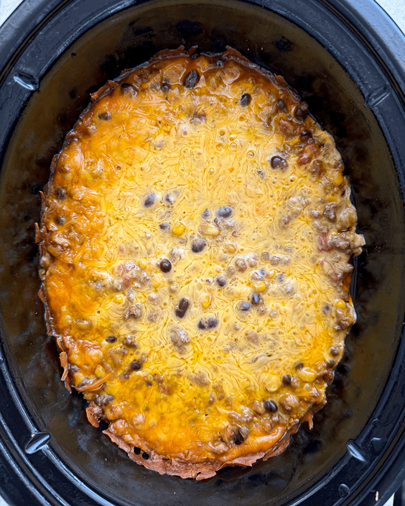 overhead shot of cooked slow cooker beef taco casserole in a black slow cooker