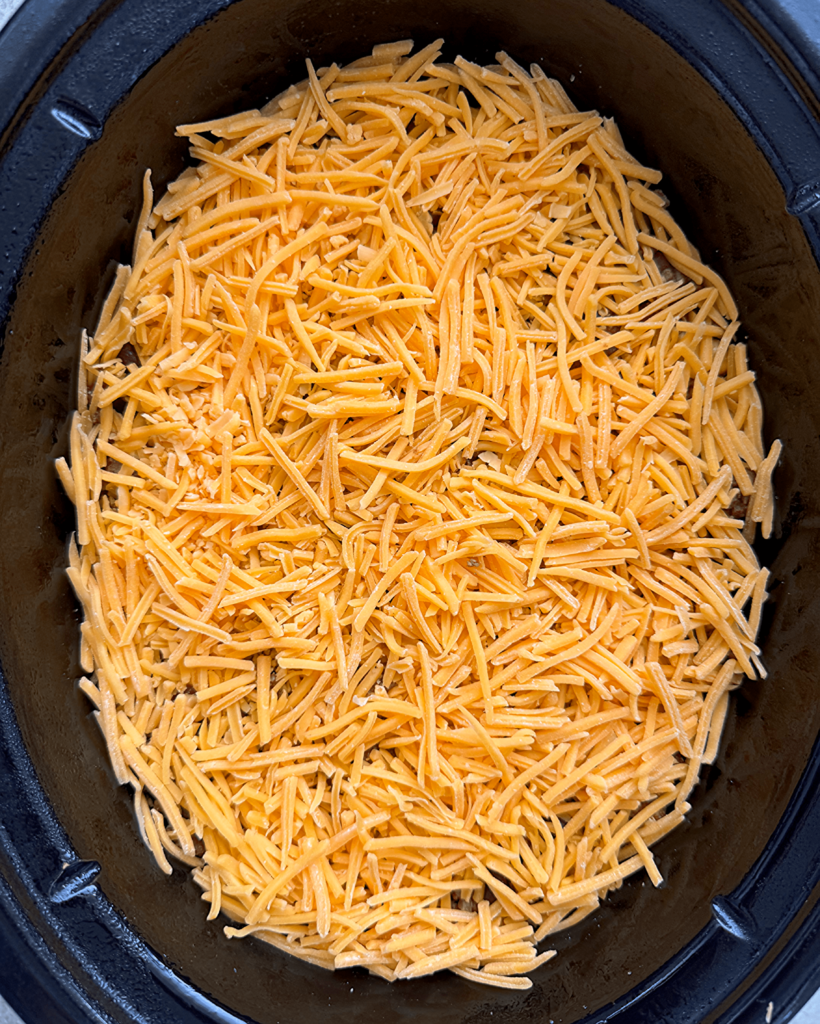overhead shot of uncooked slow cooker beef taco casserole in a black slow cooker