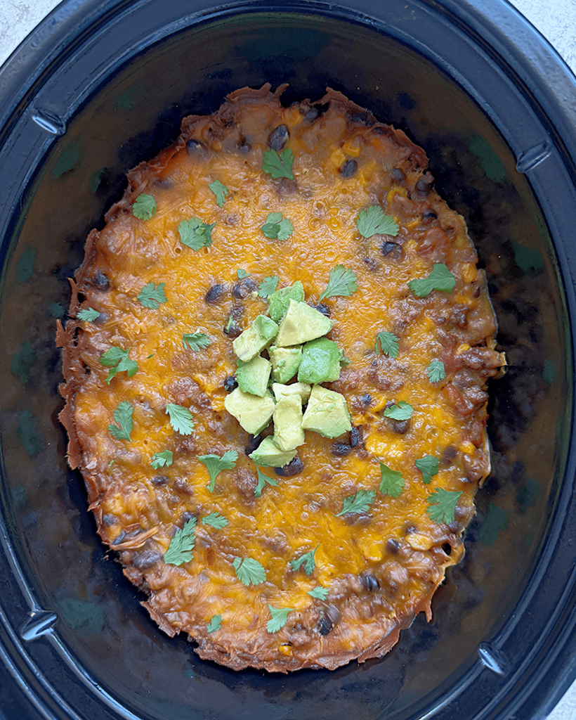 close up shot of beef taco casserole garnished with fresh cilantro and diced avocado