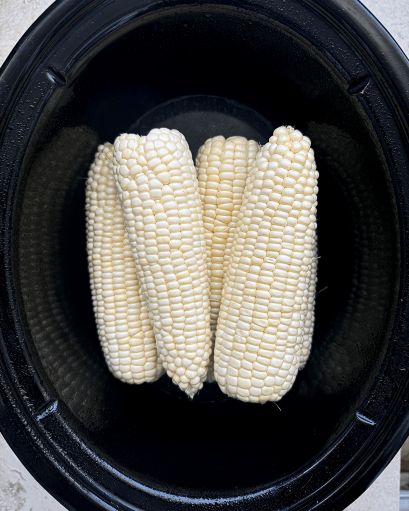 overhead shot of uncooked corn in a black slow cooker