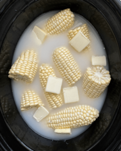 overhead shot of uncooked milk boiled corn in a black slow cooker