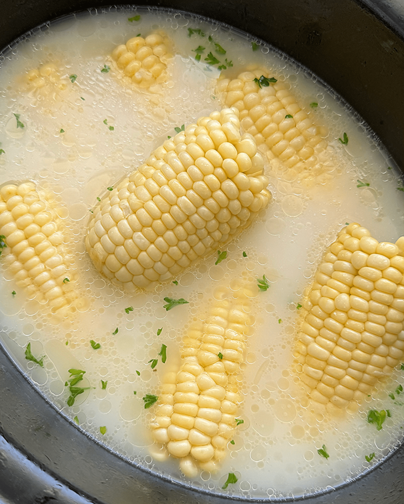 overhead shot of cooked milk boiled corn in a black slow cooker