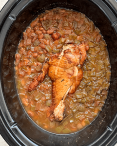 overhead shot of cooked Slow Cooker Southern Pinto Beans with smoked turkey in a black slow cooker