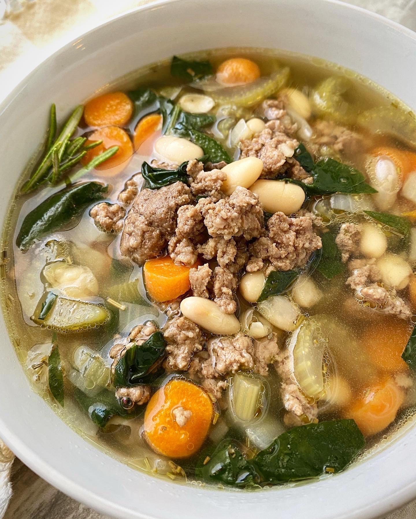 close up shot of beef bean spinach soup in a white bowl