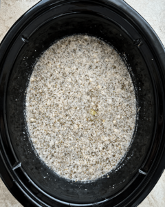 overhead shot of uncooked vegetable tortellini soup in a black slow cooker