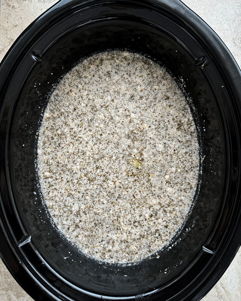 overhead shot of uncooked vegetable tortellini soup in a black slow cooker