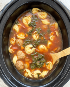 overhead shot of cooked Meatball Tortellini Soup in a black slow cooker
