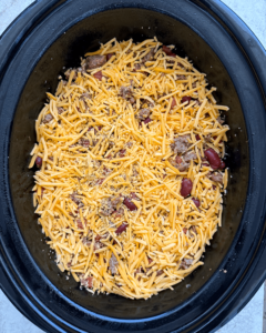 overhead shot of uncooked chili casserole in a black slow cooker