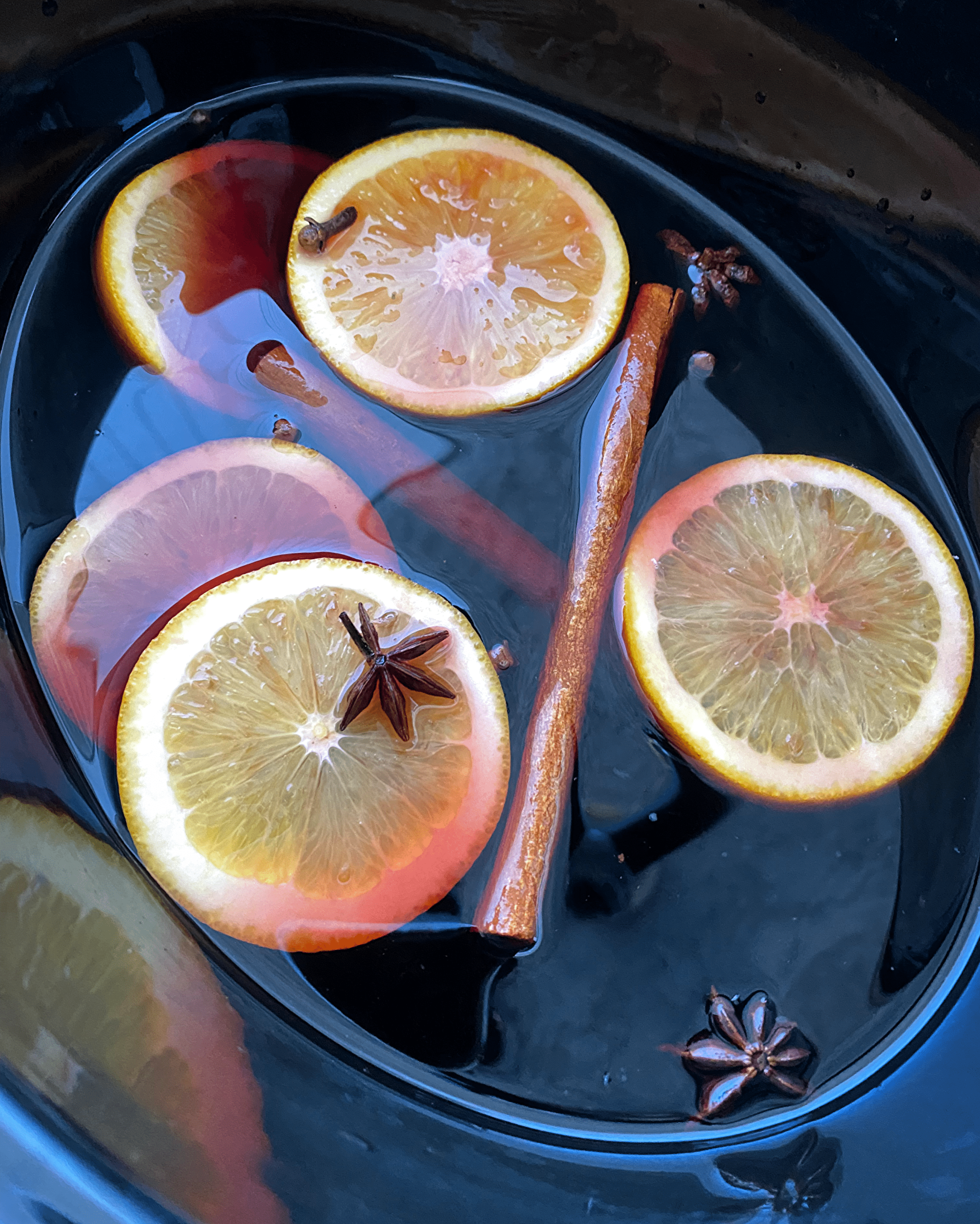 overhead shot of uncooked mulled wine in a black slow cooker