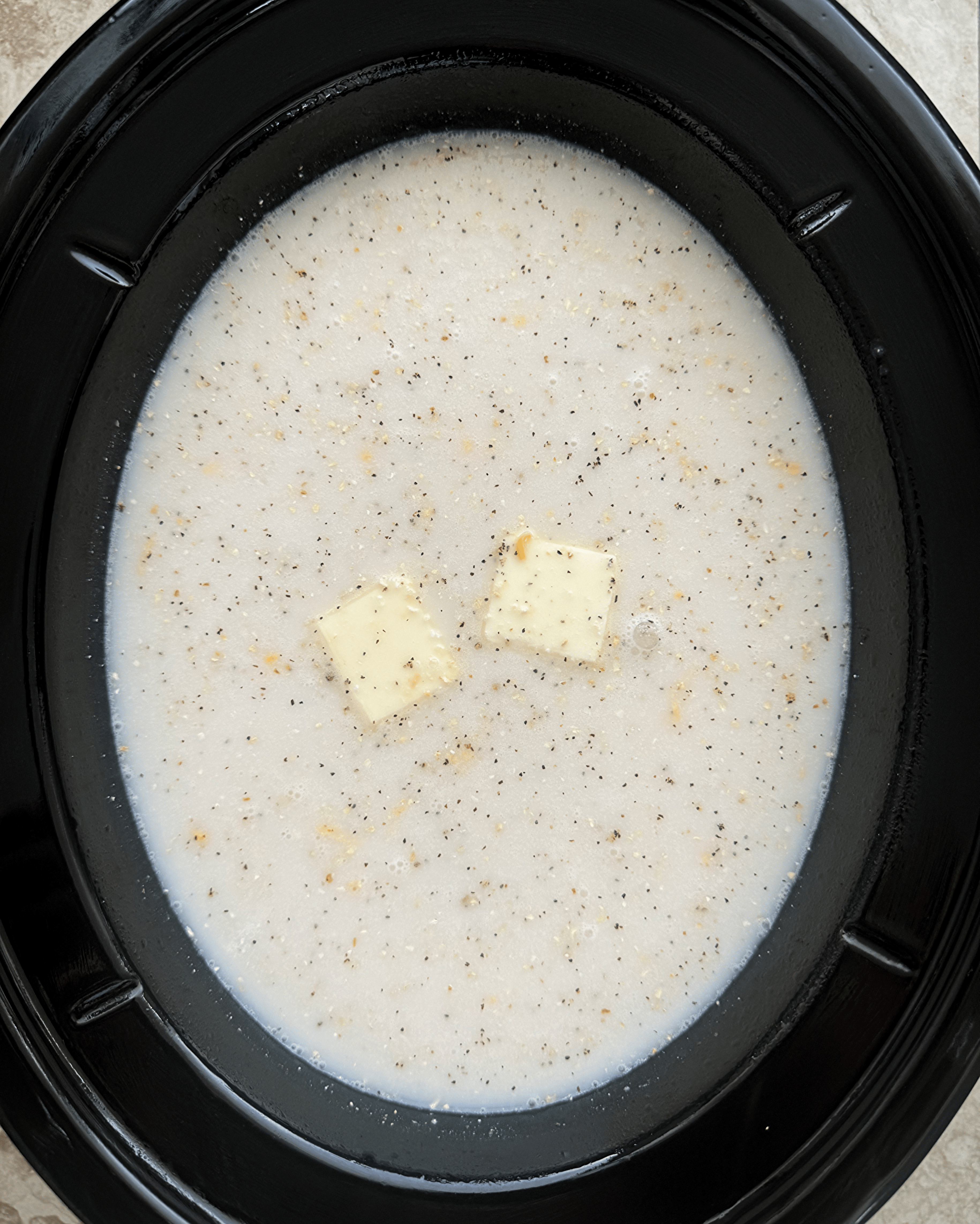 overhead shot of uncooked grits in a black slow cooker