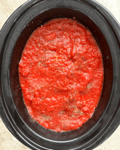 overhead shot of uncooked ravioli casserole in a black slow cooker