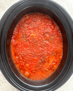 overhead shot of cooked ravioli casserole in a black slow cooker