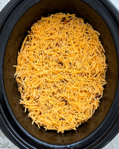 overhead shot of uncooked slow cooker vegetarian enchilada casserole in a black slow cooker