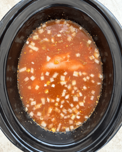 overhead shot of uncooked chicken taco soup in a black slow cooker