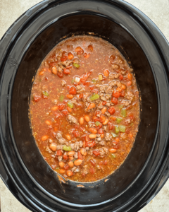 overhead shot of uncooked Chili Mac And Cheese in a black slow cooker