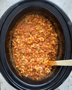 overhead shot of cooked Chili Mac And Cheese in a black slow cooker