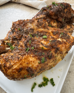 close up shot of one cooked bone-in chicken breast on a white plate