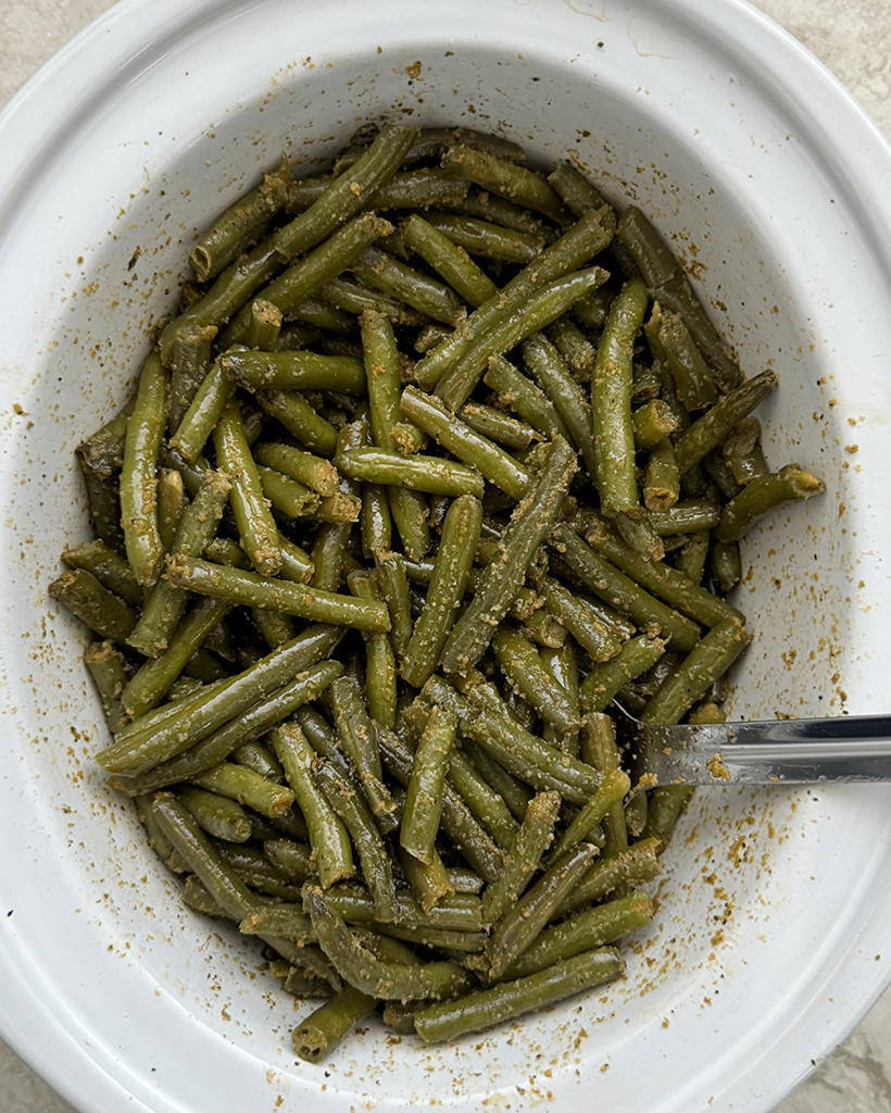 overhead shot of cooked crockpot Green Beans in a white slow cooker
