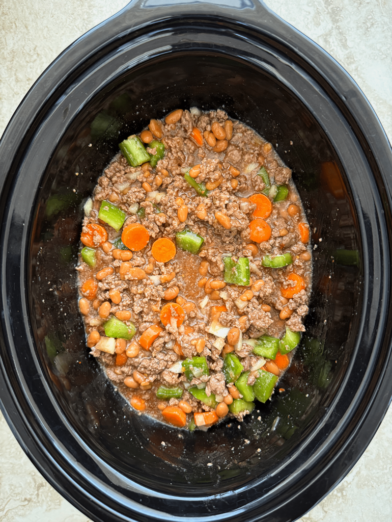 overhead shot of uncooked chuck wagon stew in a black slow cooker