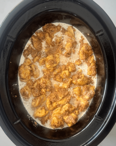 overhead shot of uncooked Cinnamon Roll Casserole in a black slow cooker