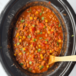 overhead shot of cooked taco chili in a black slow cooker garnished with fresh cilantro