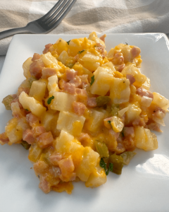 close up shot of cooked cheesy breakfast potatoes on a white plate
