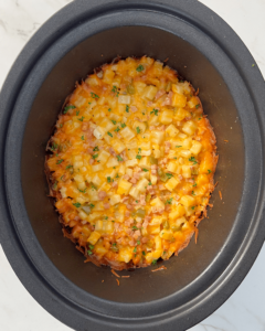 overhead shot of cooked Cheesy Breakfast Potatoes in a black slow cooker