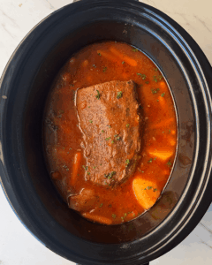 overhead shot of cooked Eye of Round Roast in a black slow cooker
