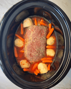 overhead shot of uncooked Eye of Round Roast in a black slow cooker