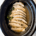 overhead shot of cooked, sliced boneless turkey breast in a black slow cooker