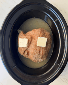 overhead shot of uncooked boneless turkey breast in a black slow cooker