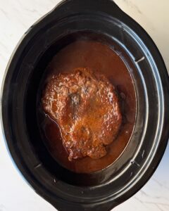 overhead shot of cooked BBQ Shredded Beef in a black slow cooker