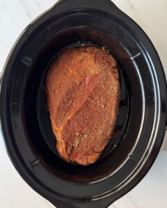 overhead shot of uncooked Beef in a black slow cooker