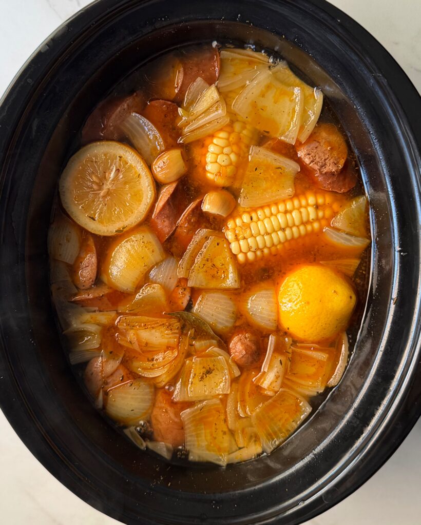 overhead shot of cooked shrimp boil in a black slow cooker without the shrimp