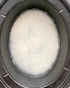 overhead shot of uncooked white rice in a black slow cooker