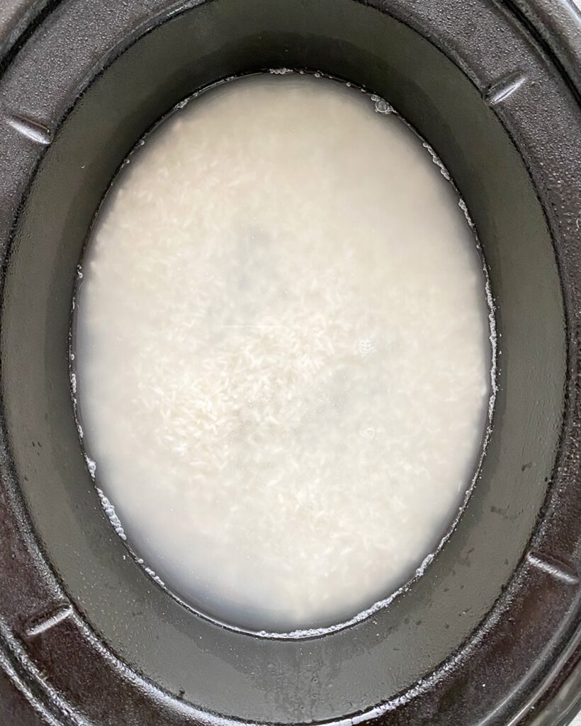 overhead shot of uncooked white rice in a black slow cooker